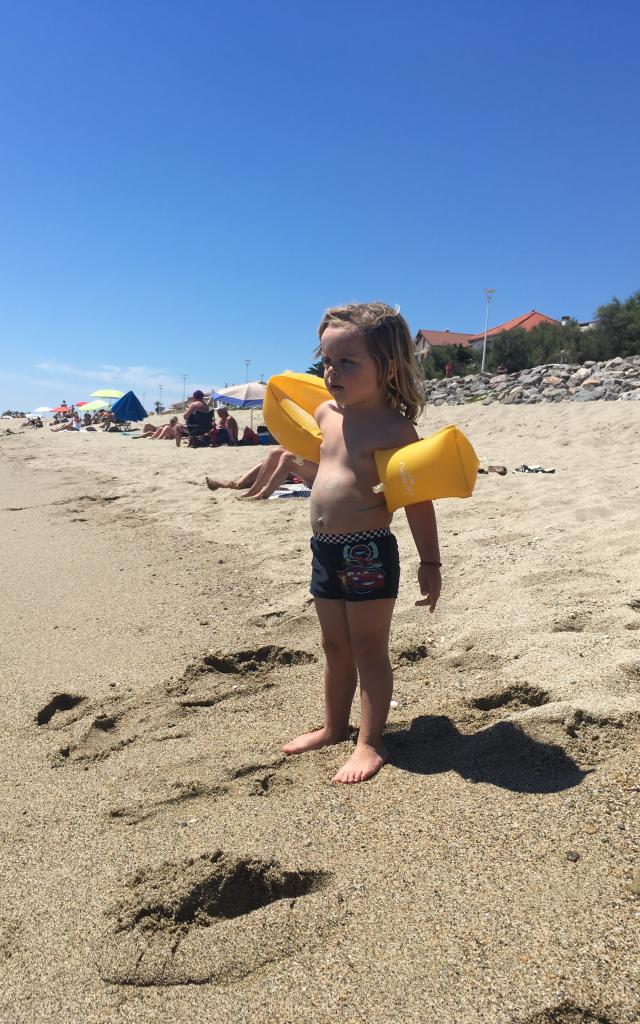 Photo d'un enfant avec ses brassards sur la plage de Leucate Plage