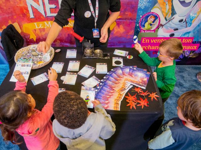 Photo d'enfants jouant avec des cartes et magazines sur une table pendant le festival Voix d'Etoiles à Port Leucate